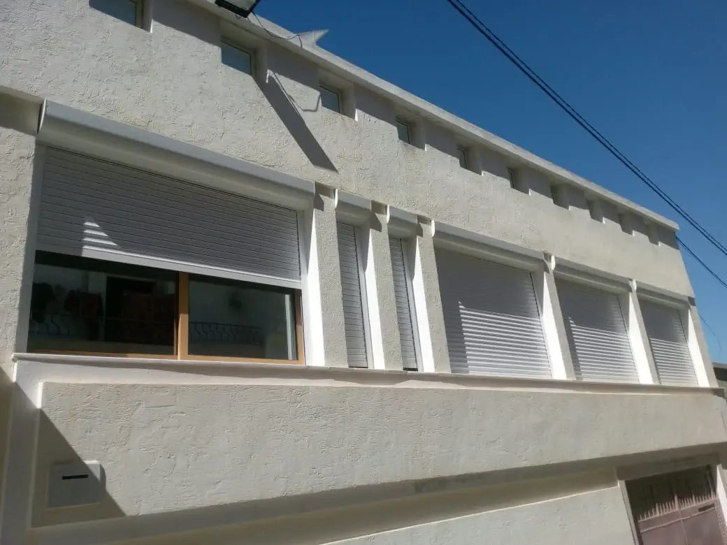Façade d'une maison équipée de plusieurs volets roulants en aluminium à coffre extérieur blanc