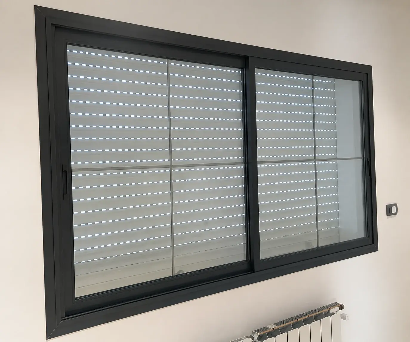 Fenêtre coulissante en aluminium gris anthracite à deux vantaux avec petits-bois, volet roulant en arrière-plan