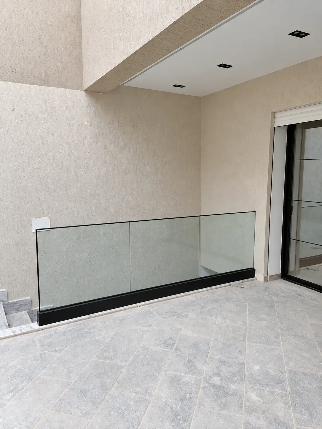 Garde-corps en verre clair fixé dans un profil noir au sol, autour d'une trémie d'escalier